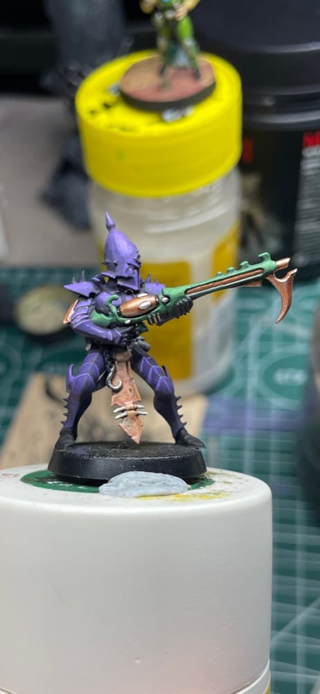 A purple Drukhari kabalite warrior with a copper and green splinter rifle